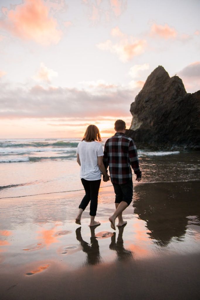 Couple Walking on Beach While Holding Hands